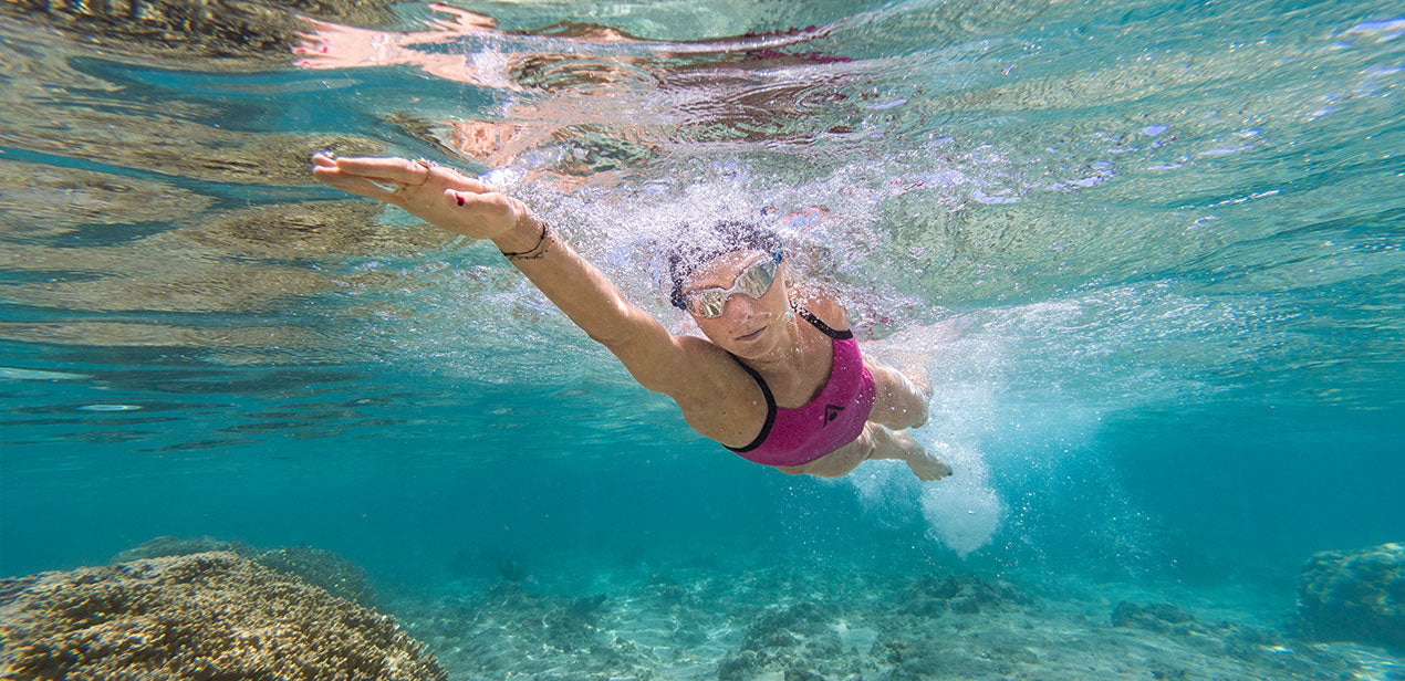 Marjolaine Pierré swimming underwater with goggles and pink swimsuit